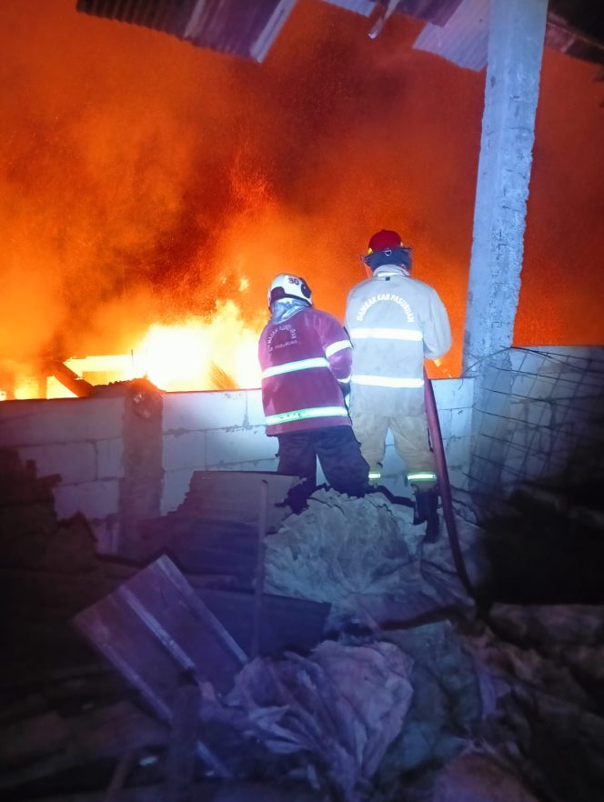 
					Petugas saat berusaha memadamkan api yang berkobar didalam gudang