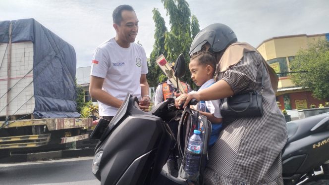 
					Normadi Elfajr, saat membagikan bunga kepada pengguna jalan di alun-alun bangil