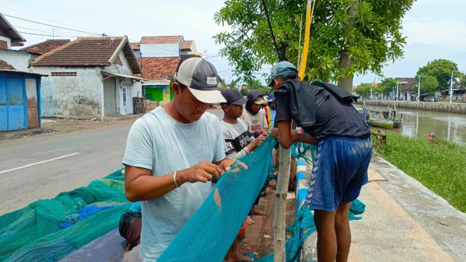 
					Para nelayan yang mengisi waktu dengan memperbaiki jala