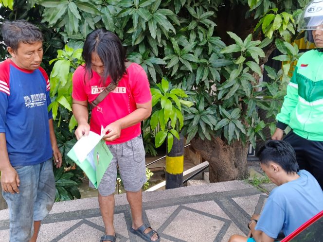 
					Petugas dari Satresnarkoba Polres Pasuruan Kota saat menunjukkan surat penangkapan kepada pelaku