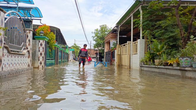 
					Warga yang melintas ditengah genangan air banjir